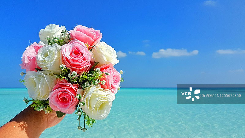 海滩上，新娘手捧婚礼花束，幸福的一天图片素材