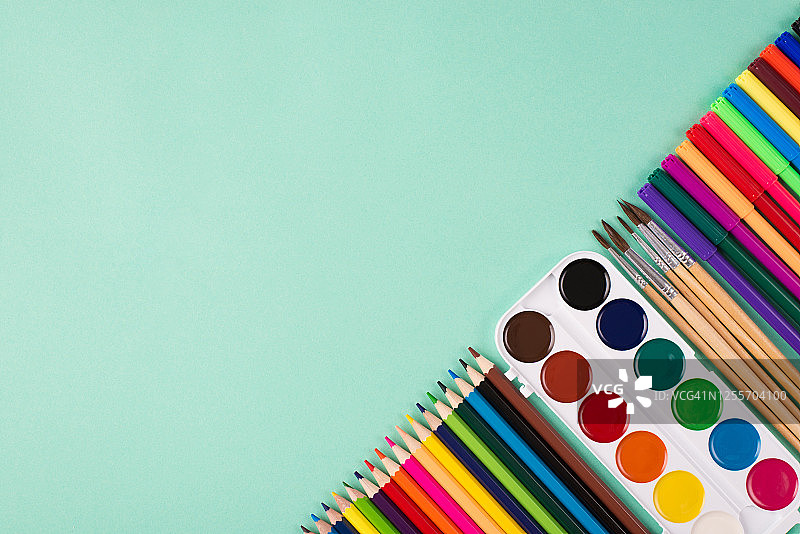 绘画用品概念：彩色文具俯视图，背景为蓝绿色，带有文案空间图片素材