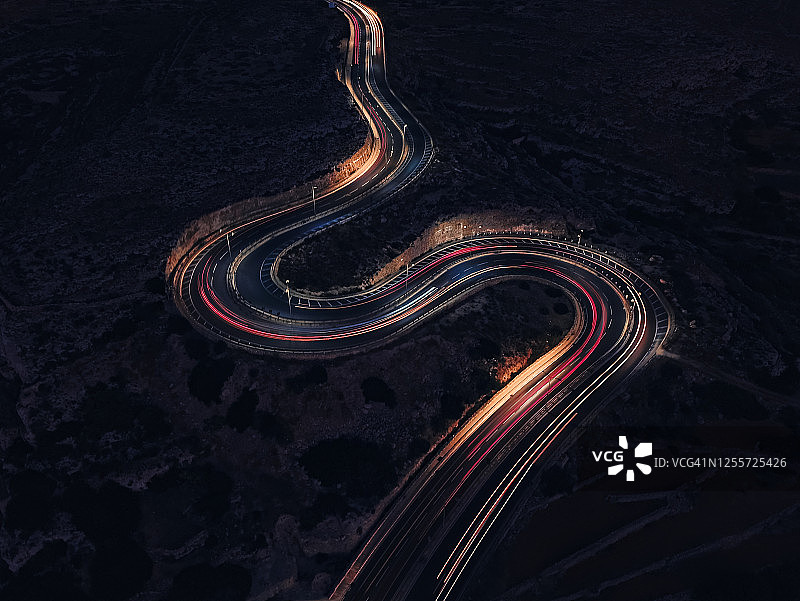 夜间S形乡村道路上车灯轨迹的航拍图片素材