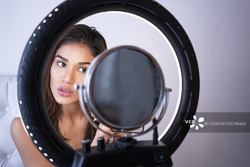 疫情期间在家通过YouTube学习化妆的拉丁裔女性图片素材