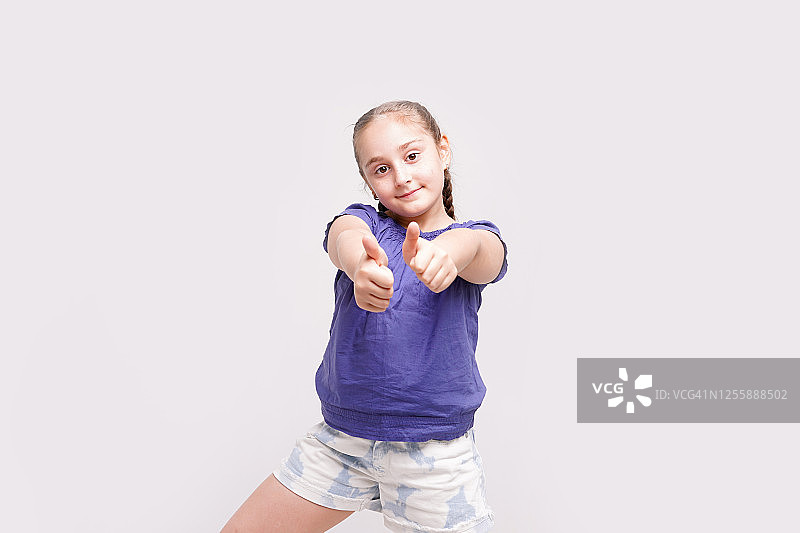 一个聪明的孩子在白色背景下竖起大拇指的肖像，展示了它的样子图片素材