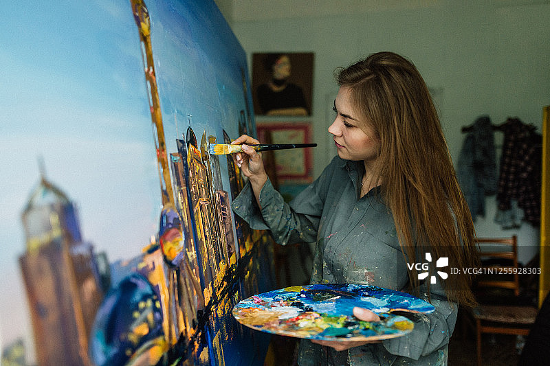 年轻白人女子在家中艺术工作室绘画城市景观图片素材