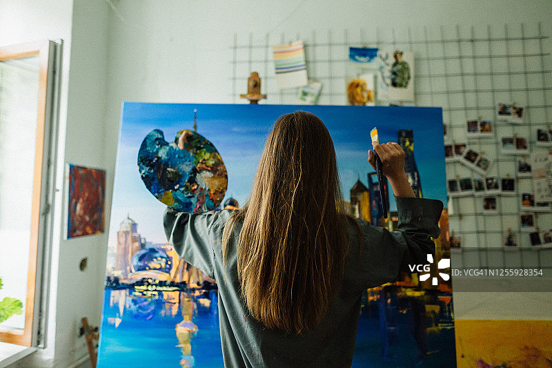 年轻白人女子在家中艺术工作室绘画城市景观图片素材