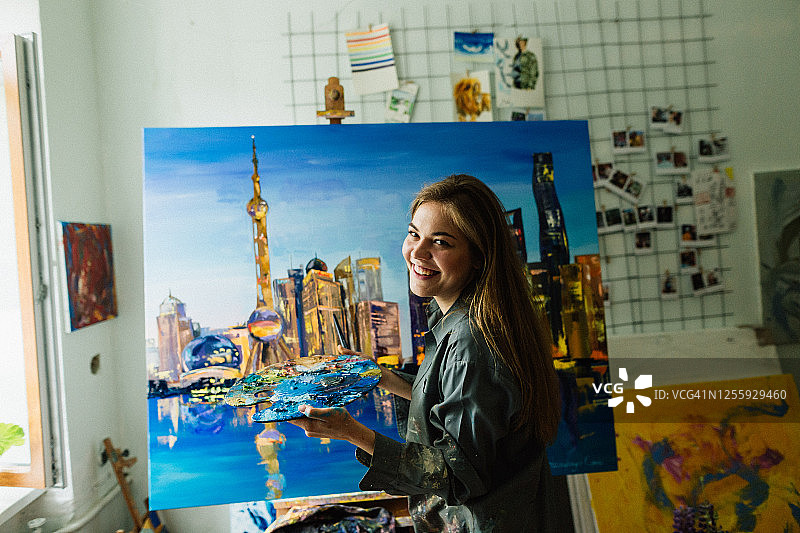 年轻白人女子在家中艺术工作室绘画城市景观图片素材