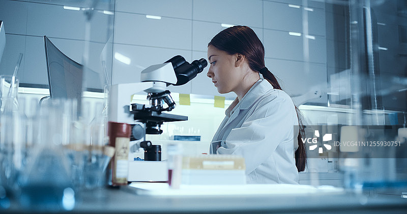研究中的女微生物学家，在未来实验室使用显微镜图片素材