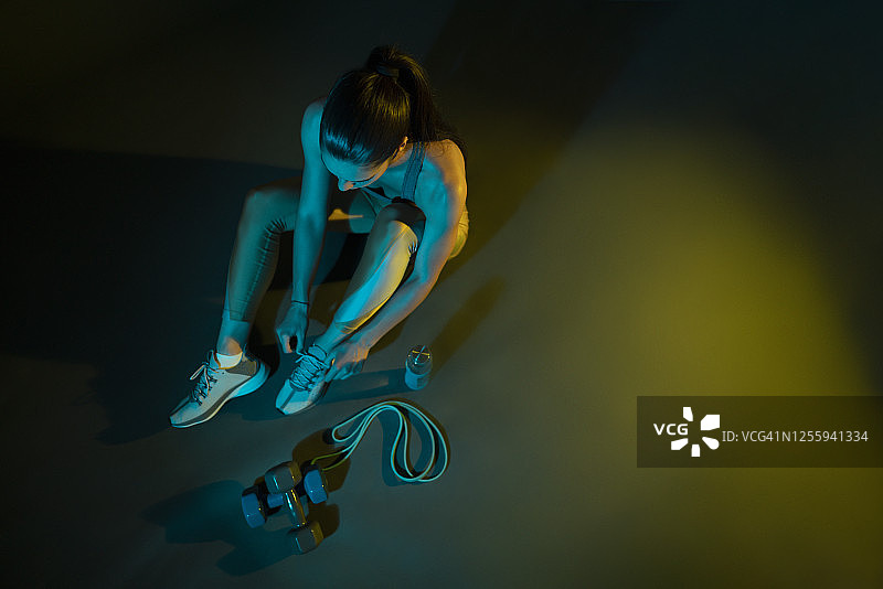 年轻女运动员系鞋带，准备训练的棚拍图片素材