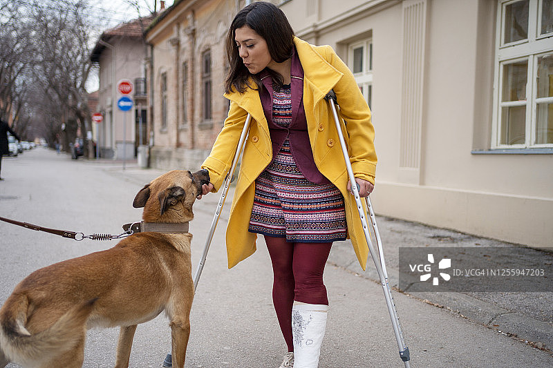 女人拄着拐杖抚摸狗图片素材