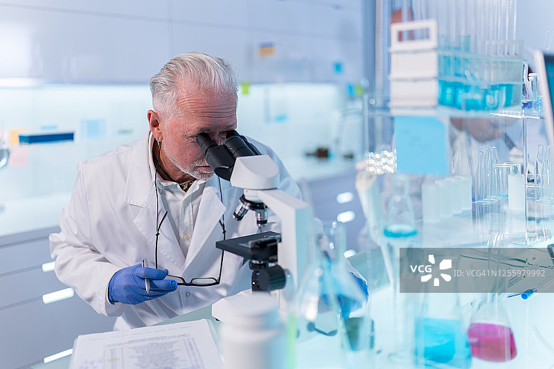 身穿防护服的实验室工作人员，专注于研究的资深医生图片素材