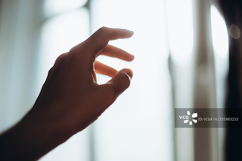 在黑暗中伸向明亮窗户的手图片素材