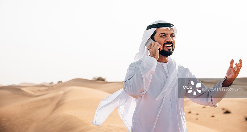在沙漠里打电话的阿拉伯男人图片素材