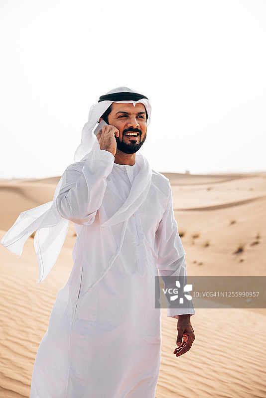 在沙漠里打电话的阿拉伯男人图片素材
