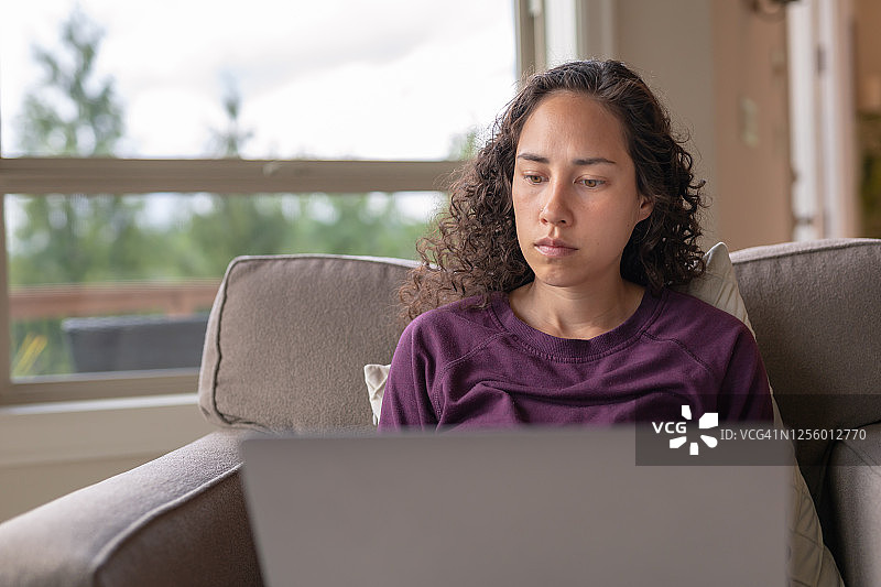 欧亚混血女人在客厅使用笔记本电脑图片素材