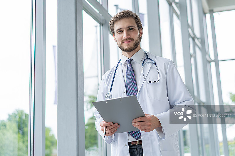 男医生站在医院里，拿着文件夹图片素材