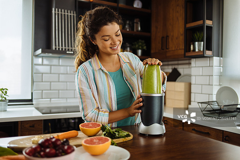 年轻女人在家准备绿色冰沙图片素材