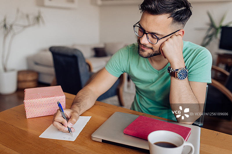 写信并为某人准备礼品盒的年轻男人图片素材