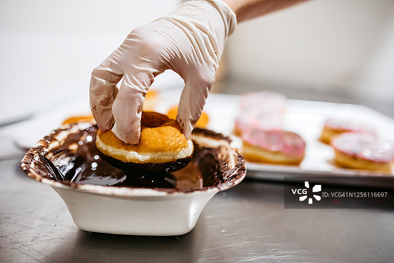 将甜甜圈放入巧克力蘸料中图片素材