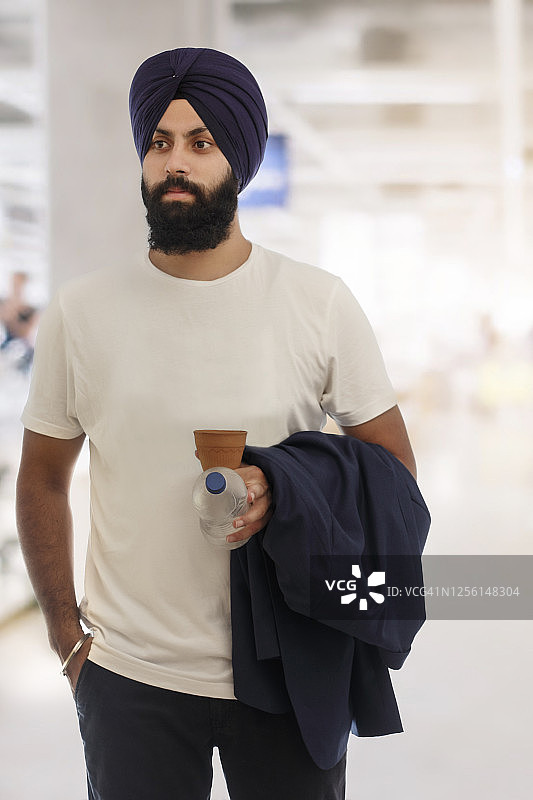 拿着泥制库尔哈德水瓶和夹克的锡克教男人图片素材