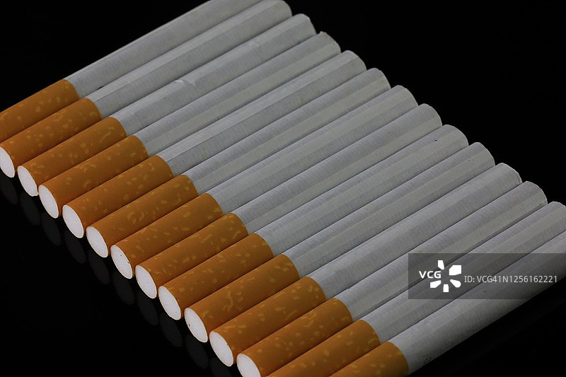 黑色背景上的一排正在燃烧的香烟图片素材