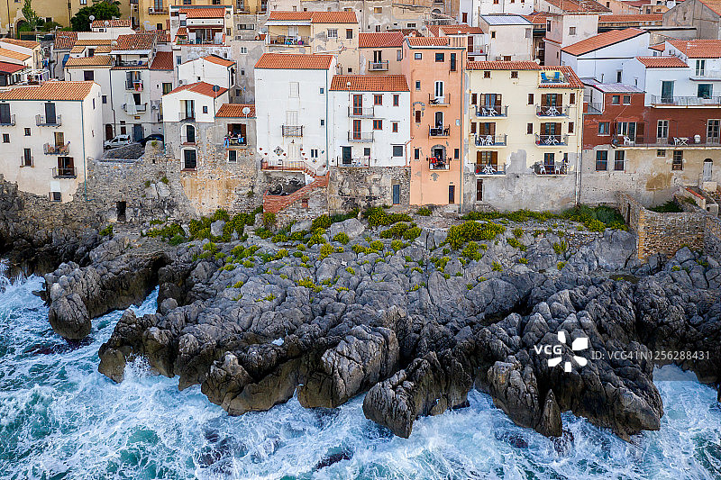 大风暴天气中，从海上拍摄的切法卢岩石海岸和房屋的航拍景色，意大利西西里岛图片素材
