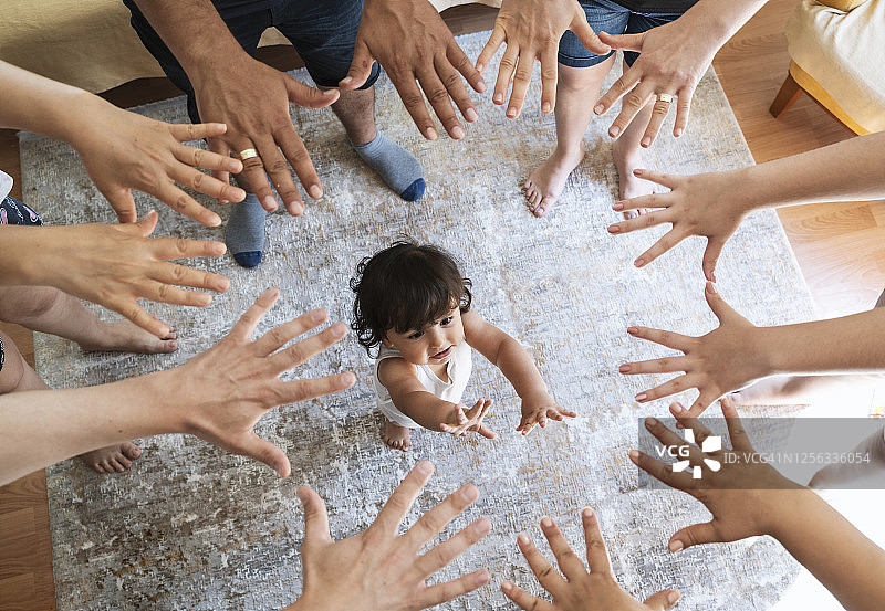 家人团结一致，将手放在一起，中间有一个男婴图片素材