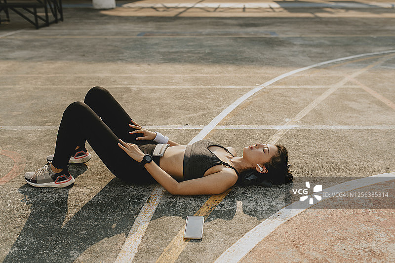 户外运动后躺在球场上休息的疲惫女运动员图片素材
