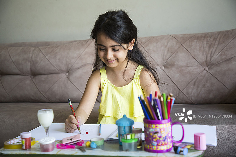 可爱的小女孩在家用彩色铅笔画画图片素材