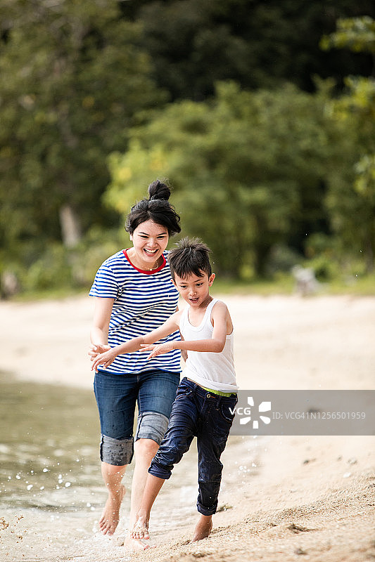 母亲在沙滩上追逐小男孩图片素材