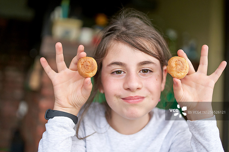 拿着泡芙在眼睛上开玩笑的美丽年轻女孩图片素材