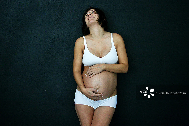 穿着内衣抚摸隆起腹部的孕妇图片素材