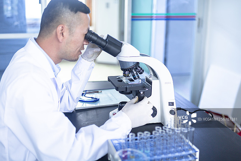 年轻男科学家在看显微镜图片素材