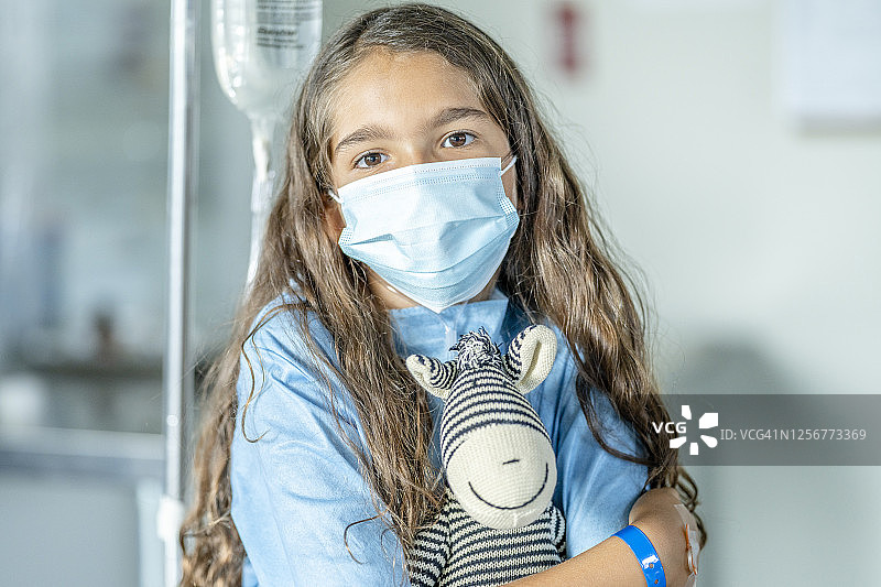小女孩和她的毛绒玩具在医院里戴着防护口罩图片素材