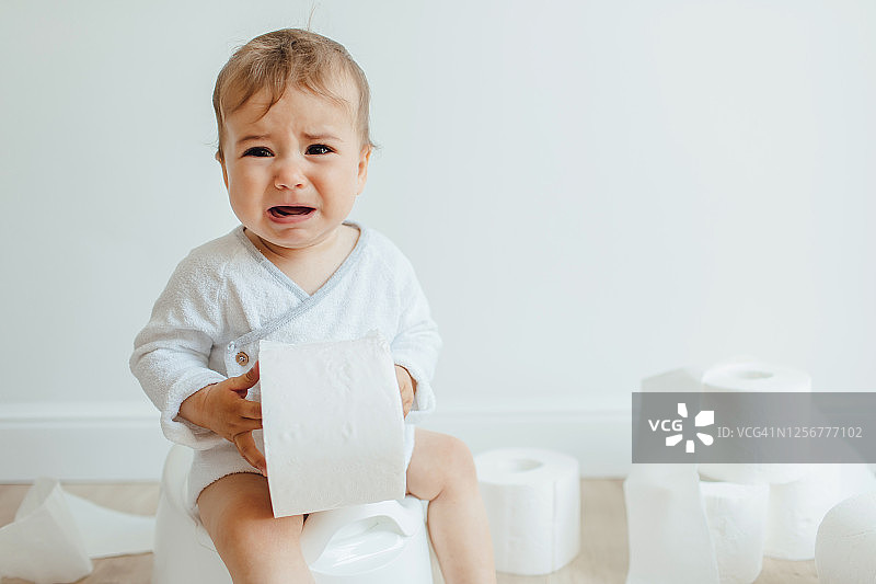 坐在白色便盆上哭泣的可爱小孩图片素材