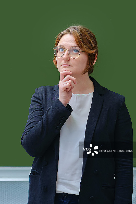 陷入沉思的学校老师站在黑板旁图片素材