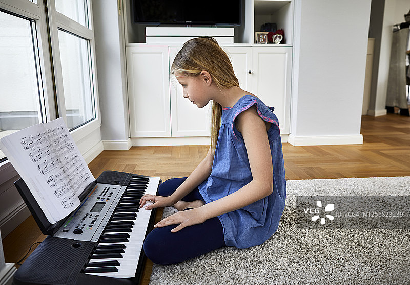 在家坐在地板上弹键盘的女孩图片素材