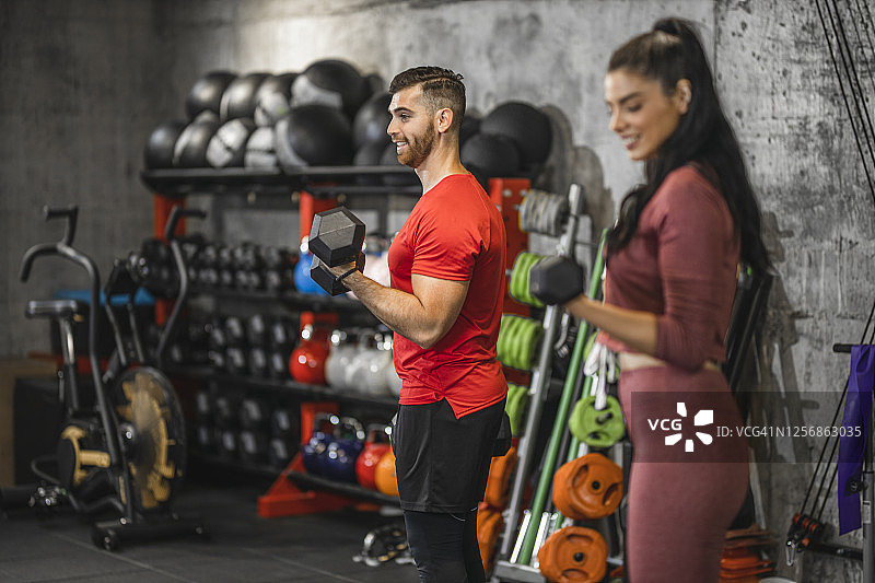 在健身房里用哑铃锻炼并微笑的美丽年轻运动员图片素材