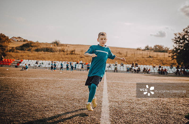 男孩在足球场上运球绕过训练锥图片素材