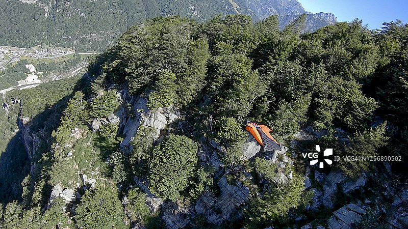 男子翼装飞行员在山间悬崖上滑翔图片素材