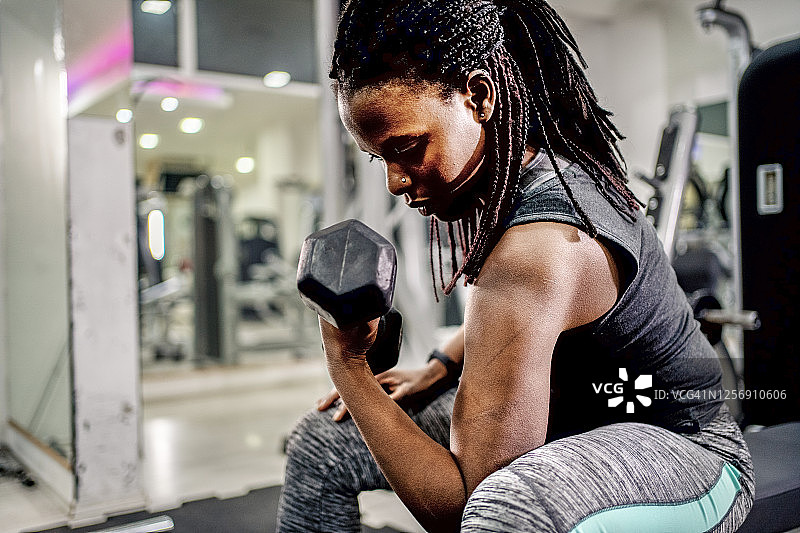 穿着运动服举哑铃的健壮黑人女孩图片素材