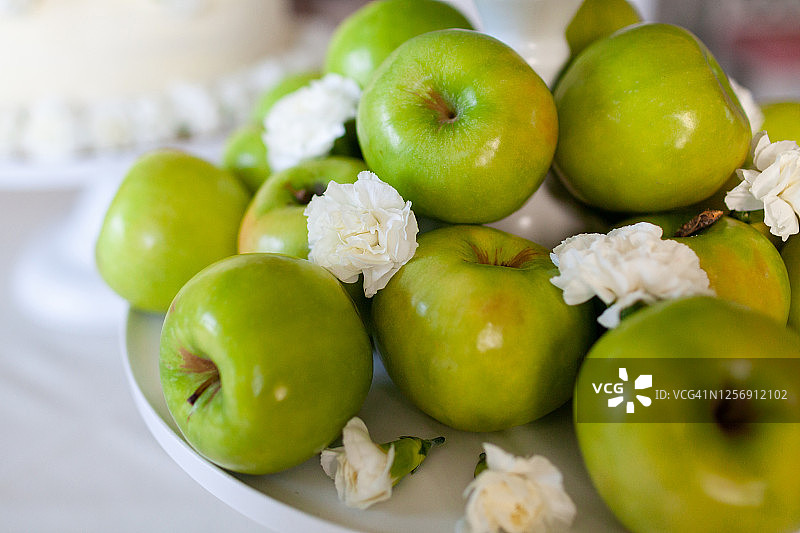 装在盘子里，配有白色鲜花的青苹果图片素材