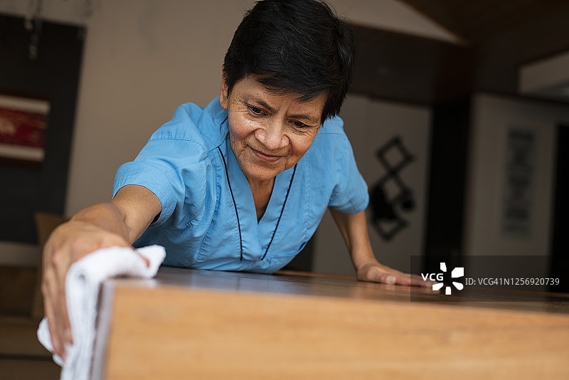拉丁裔妇女清洁所服务房屋的木桌图片素材