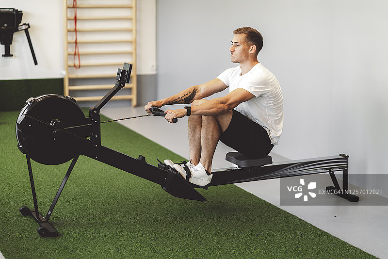 在划船机上锻炼的年轻白人男子图片素材