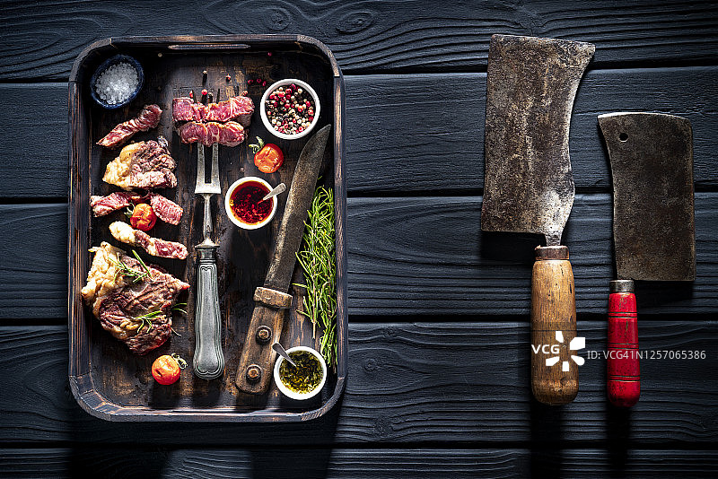 雕刻的带状牛排，顶部里脊牛排，牛肉，带有雕刻叉和刀的复古托盘图片素材