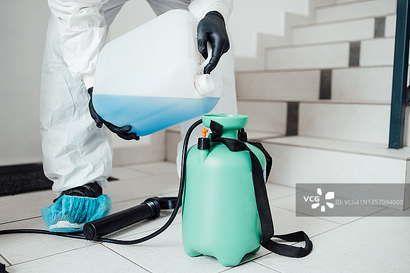 室内表面消毒清洁。建筑物内部清洁与消毒，预防新型冠状病毒。专业消毒团队进行消毒工作。预防和控制疫情感染。防护服和口罩。图片素材
