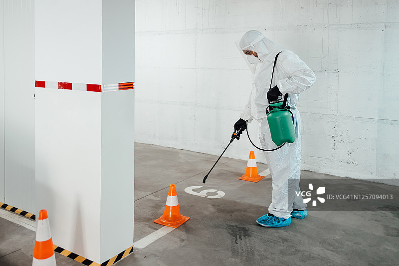 室内表面消毒清洁。建筑物内部清洁与消毒，预防新型冠状病毒。专业消毒团队进行消毒工作。预防和控制疫情感染。防护服和口罩。图片素材