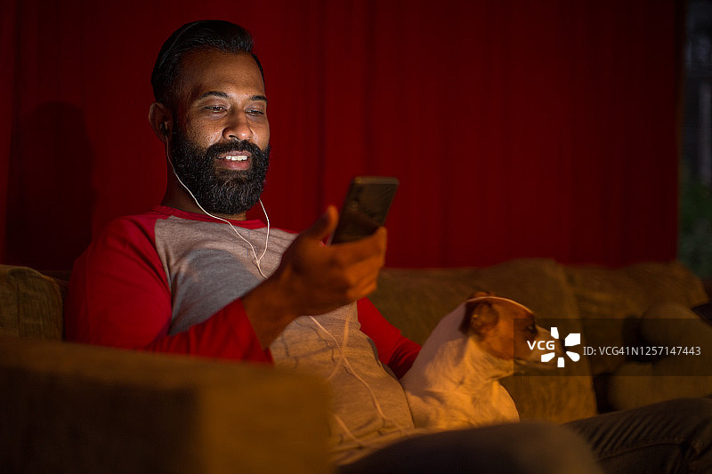 封锁期间在家看智能手机的混血男子图片素材