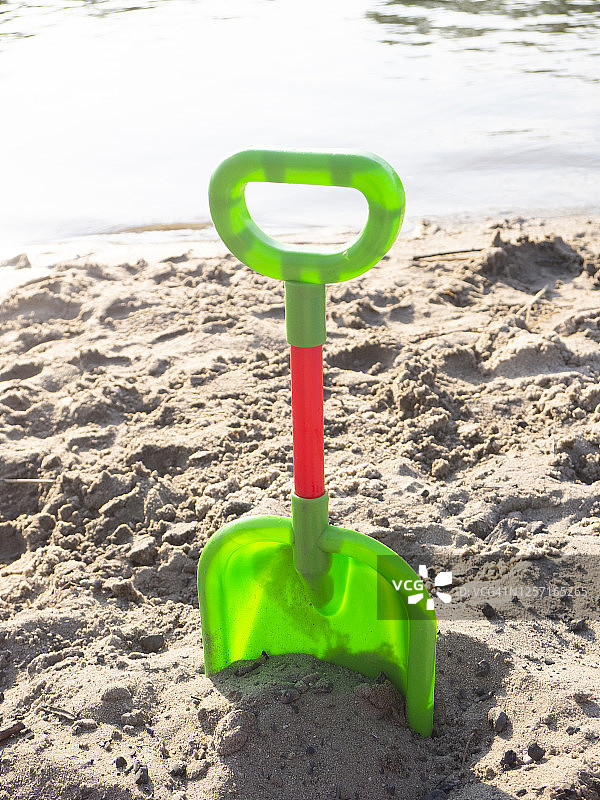 插在湖滩沙子里的玩具铲子。德国图片素材