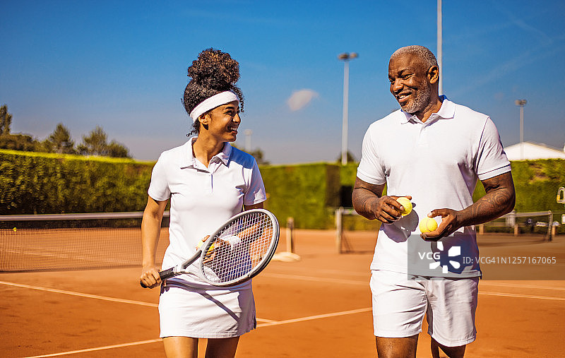 一位漂亮的女网球运动员和她的教练父亲在球场上图片素材