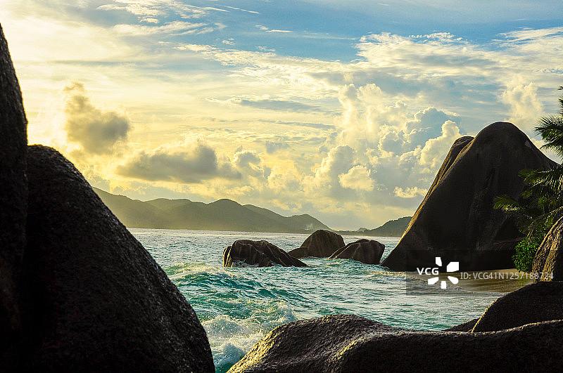 拉迪格岛岩石上的壮丽日落，海面波涛汹涌，天空多云图片素材