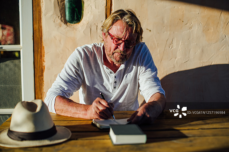 在笔记本上写作的老年男人图片素材
