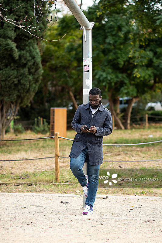 在篮球架下发短信的络腮胡男子图片素材